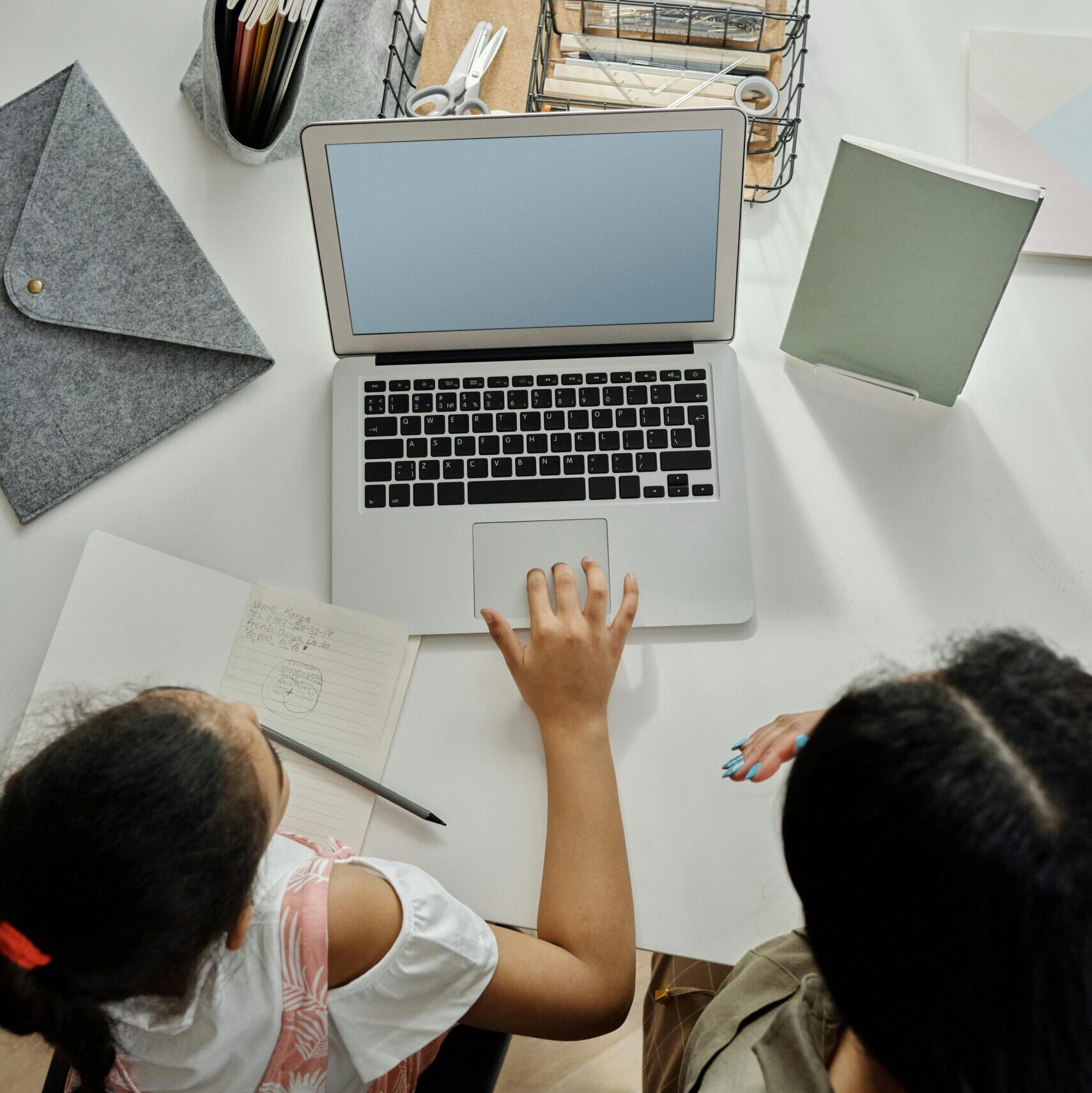 Overhead view of a mother helping her daughter with online learning at home.